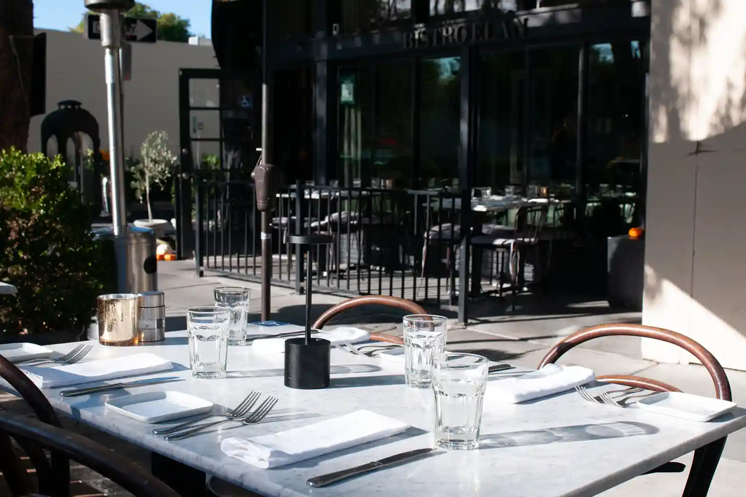 Cozy outdoor dining on the parklet facing Bistro Elan, with inviting tables surrounded by greenery near California Avenue in Palo Alto.