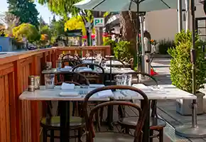 Thumbnail looking down Bistro Elan’s parklet toward Cambridge Ave, features stylish tables set for diners, creating a warm and inviting outdoor space in the heart of Palo Alto.