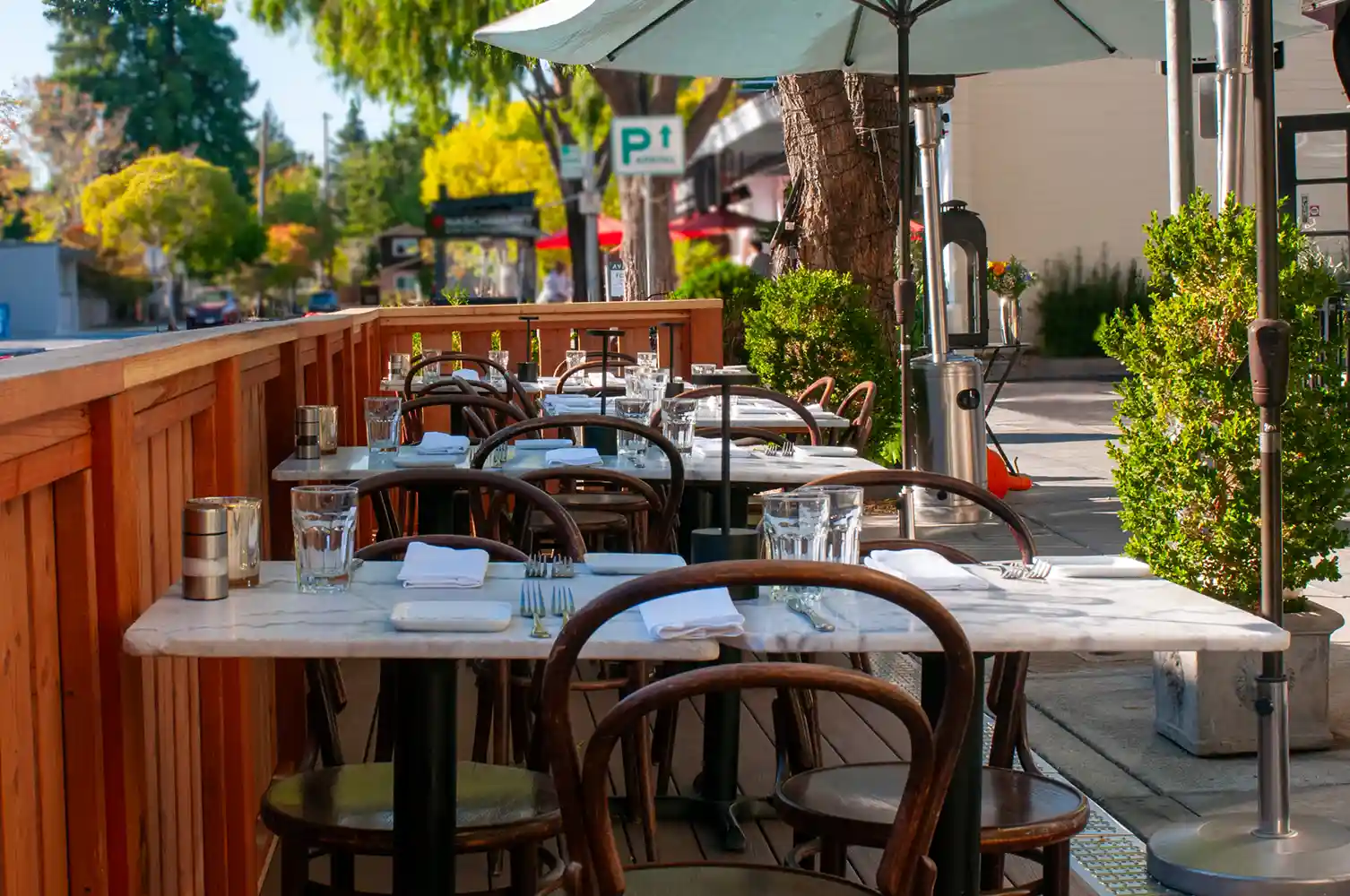 Looking down Bistro Elan’s parklet toward Cambridge Ave, features stylish tables set for diners, creating a warm and inviting outdoor space in the heart of Palo Alto.