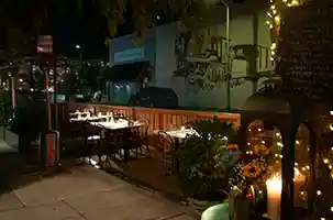 Thumbnail of a nighttime view of Bistro Elan's parklet dining area, featuring elegantly arranged tables and a welcoming ambiance, perfect for a meal near California Avenue.